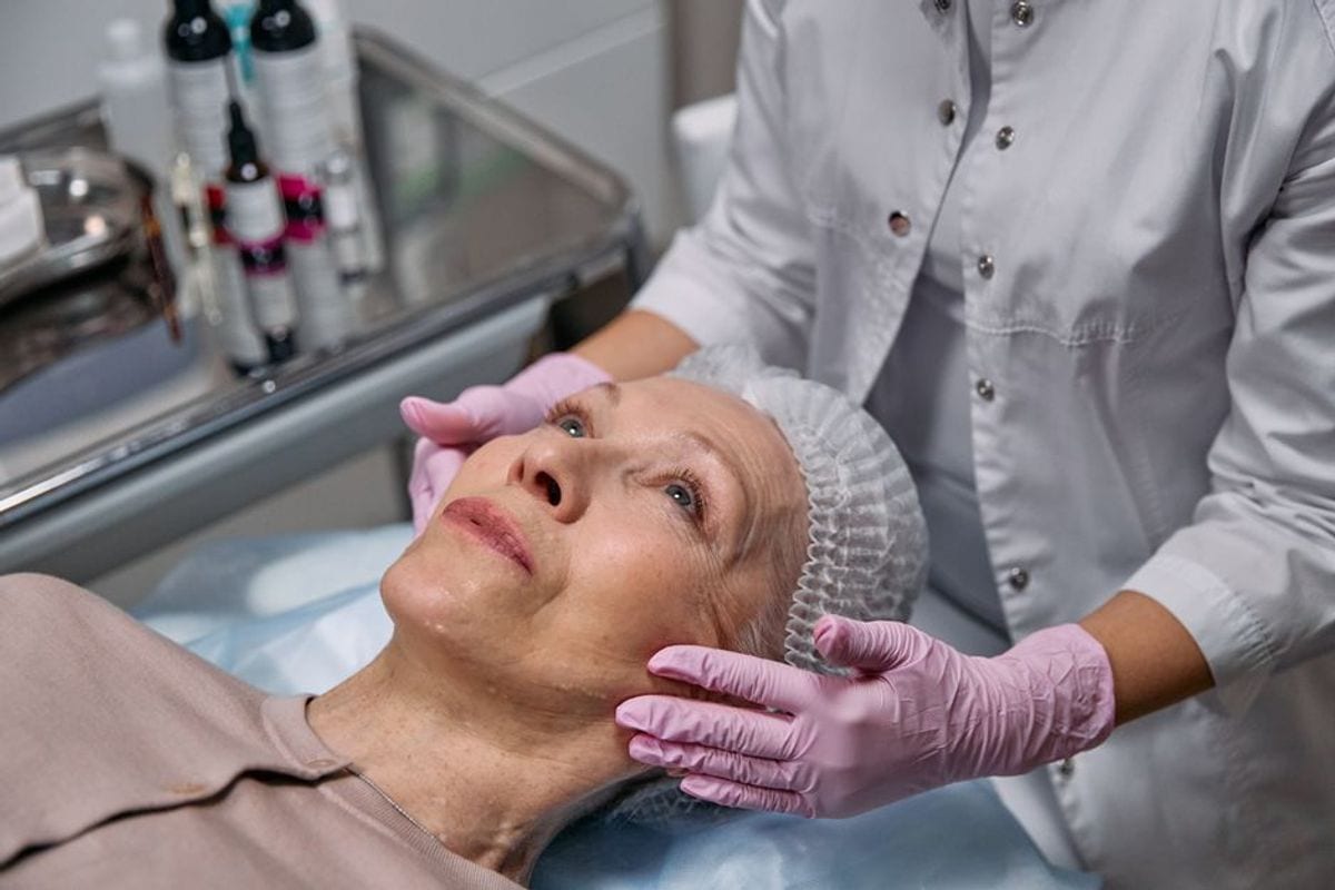 Therapist in gloves performing a facial treatment on a mature client Therapist in gloves performing a facial treatment on a mature client