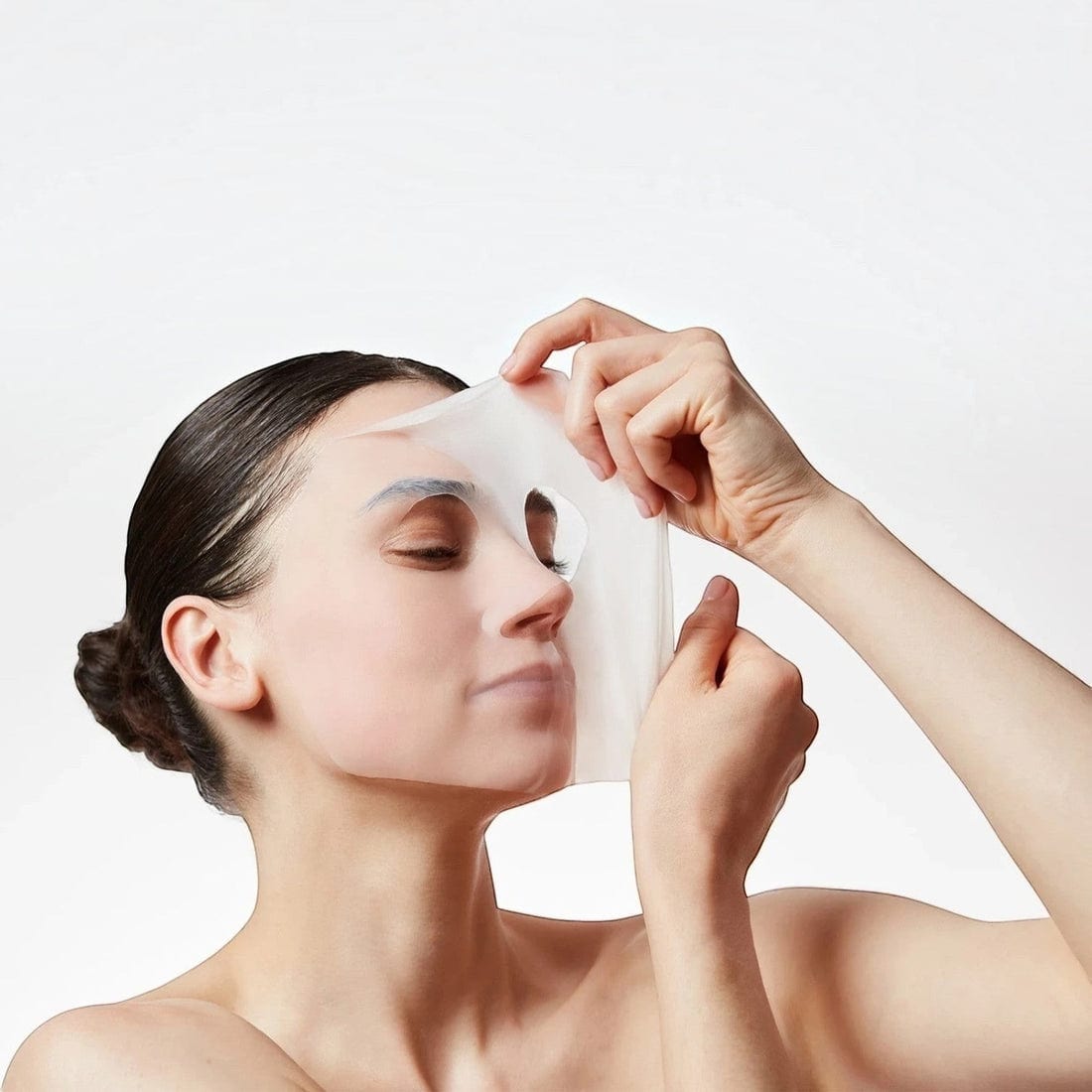Sheet mask being smoothed onto a woman's face Sheet mask being smoothed onto a woman's face