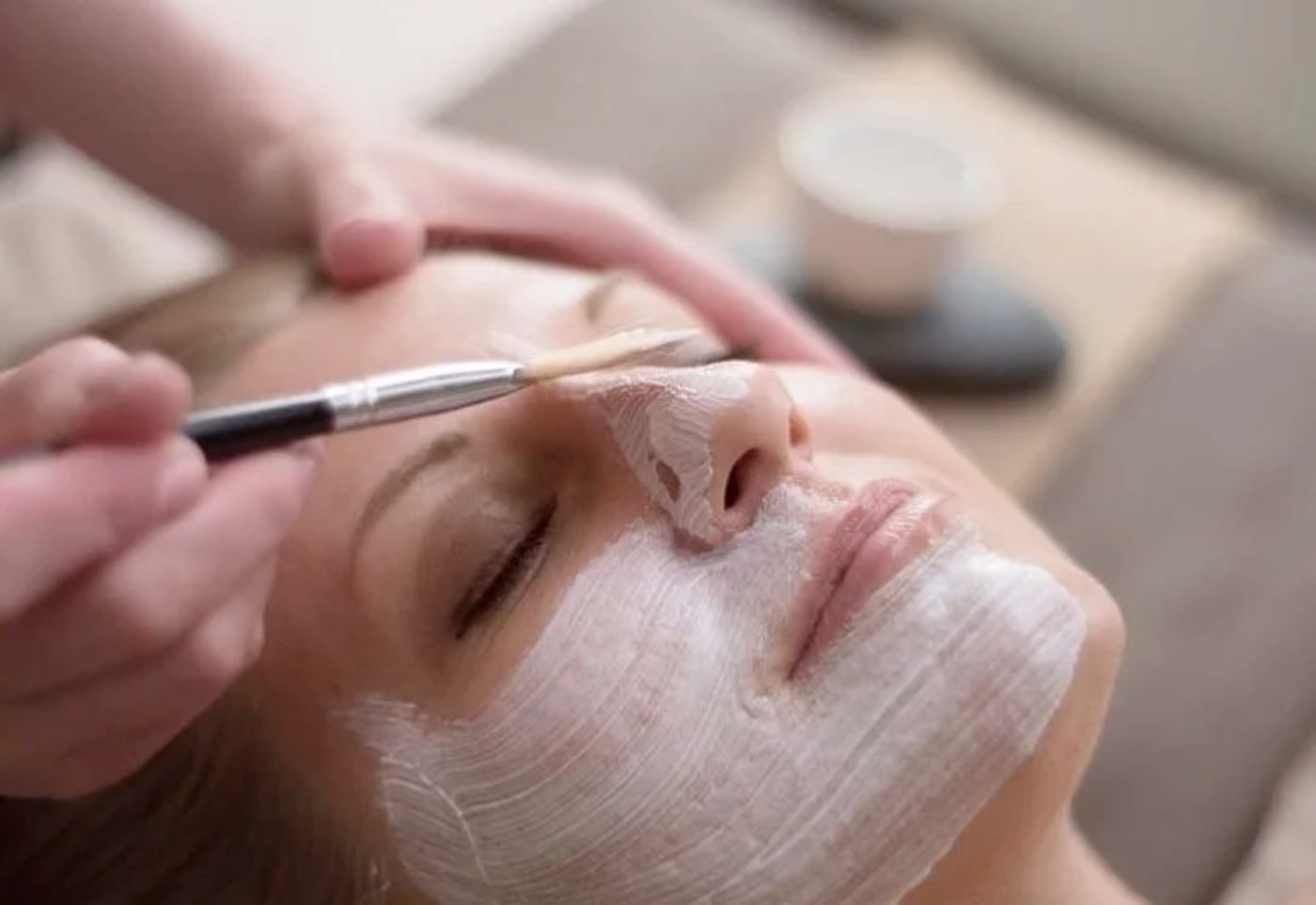 Brightening facial mask being brushed onto a client's face Brightening facial mask being brushed onto a client's face