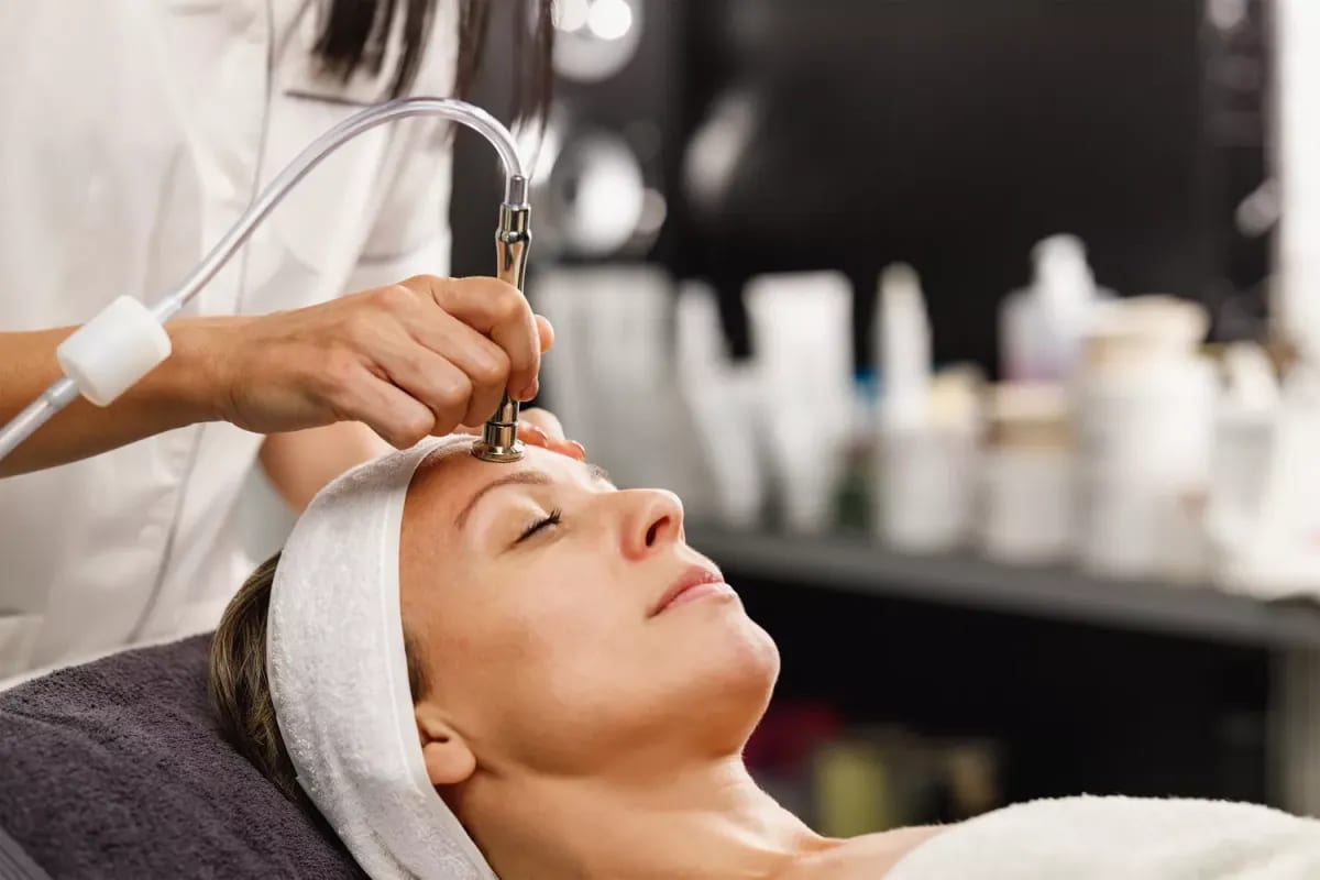 Client receiving a facial with a skin-polishing device at the salon Client receiving a facial with a skin-polishing device at the salon
