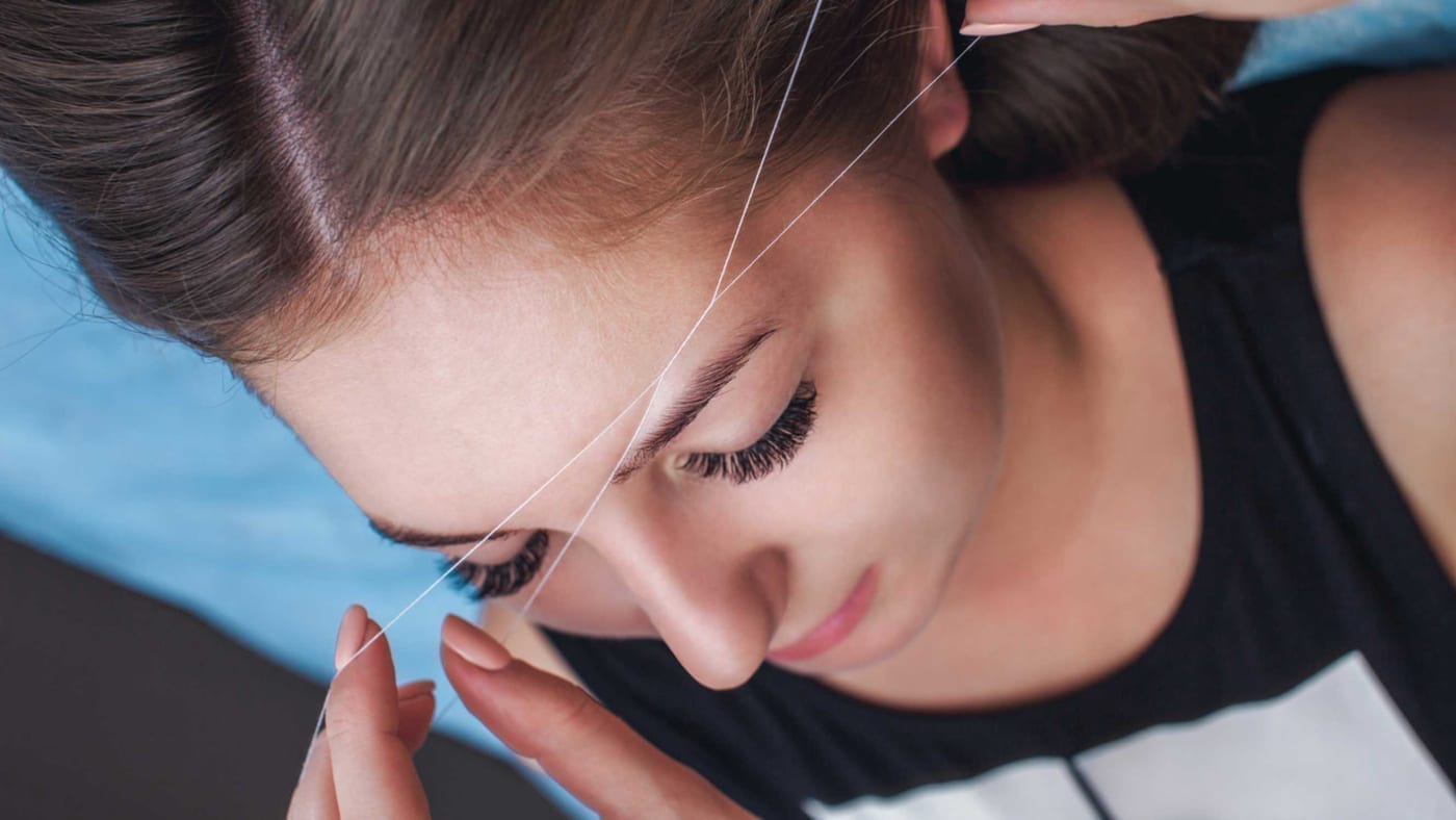 Facial hair removal being performed around a client's brow area Facial hair removal being performed around a client's brow area