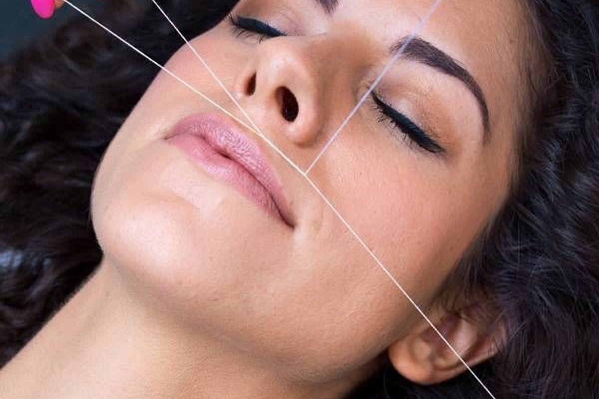 Full-face threading being performed on a reclining salon client Full-face threading being performed on a reclining salon client