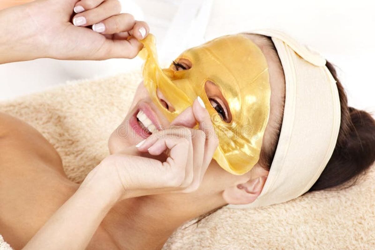 Gold facial mask being lifted from a client's face at the spa Gold facial mask being lifted from a client's face at the spa