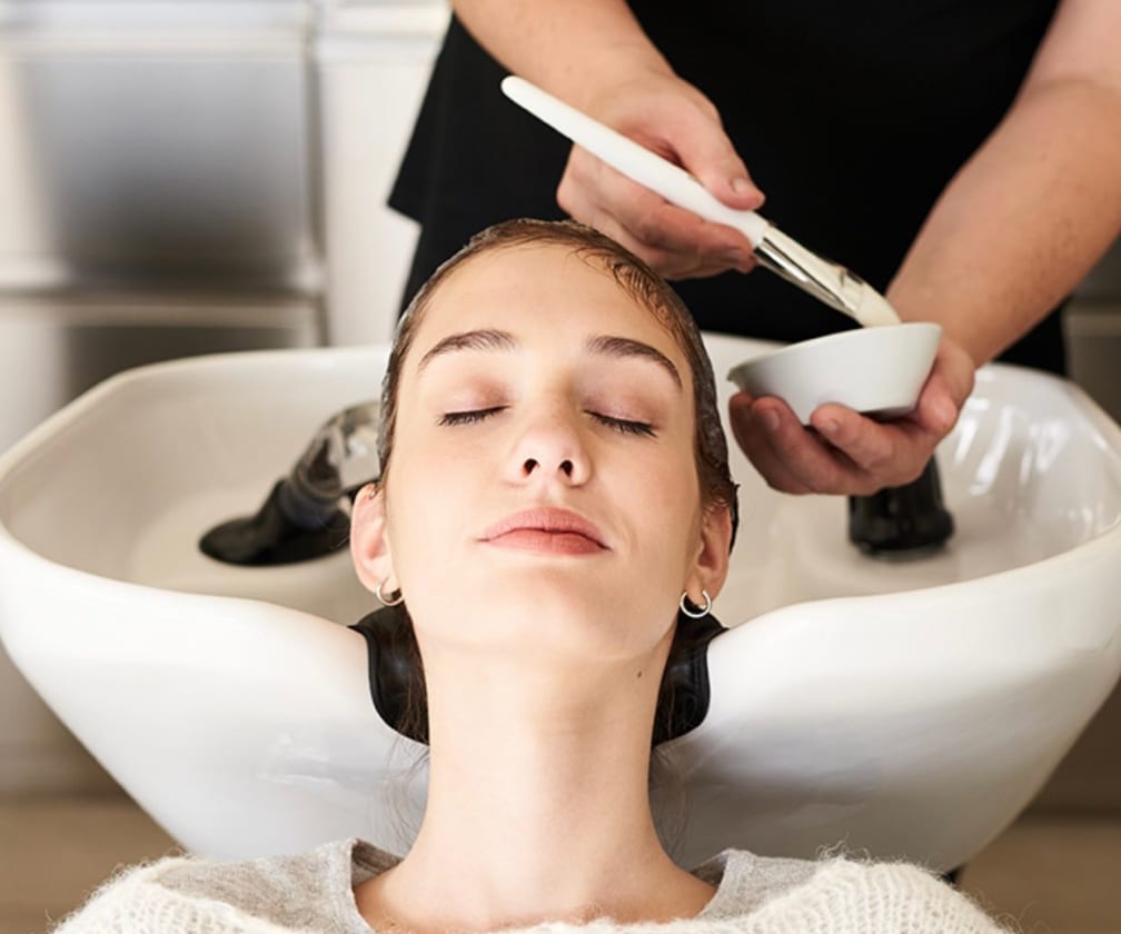 Professional applying a scalp and hair treatment in a salon