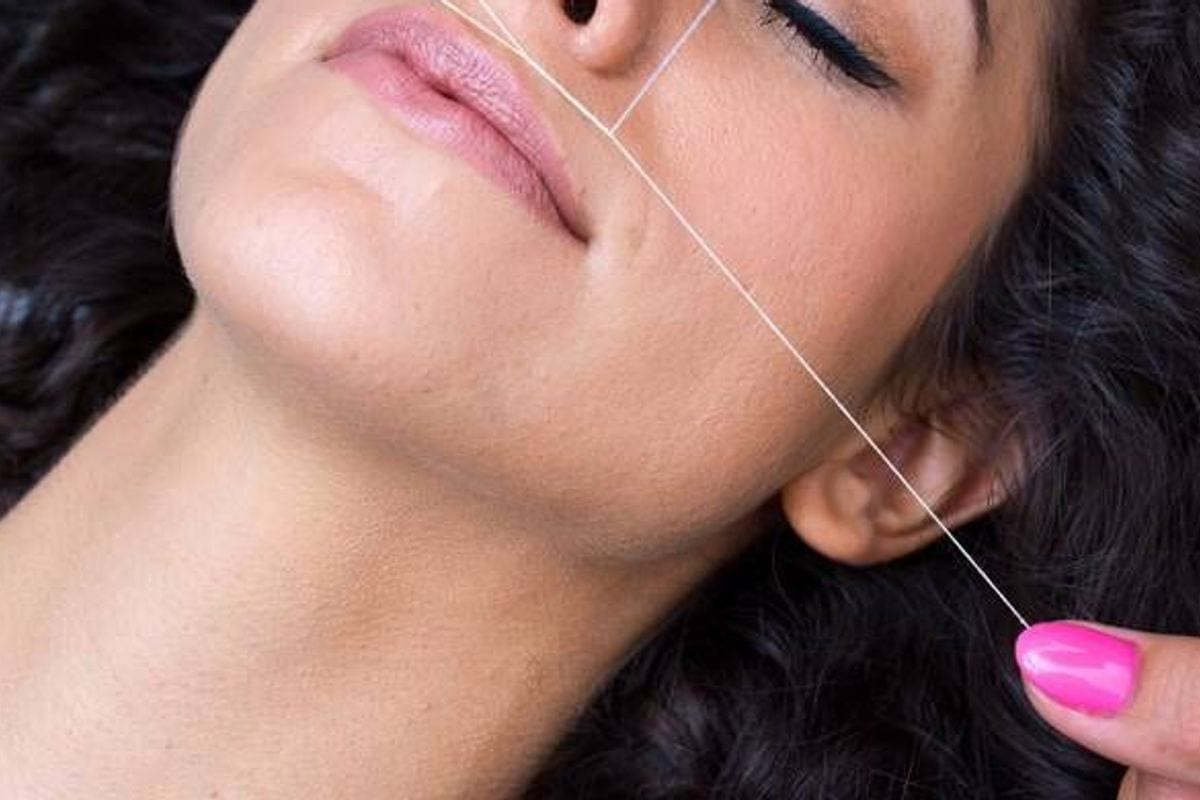 Thread positioned across the upper-lip area for hair removal Thread positioned across the upper-lip area for hair removal